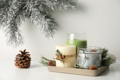 Photo of Composition with scented conifer candles and Christmas decor on white table