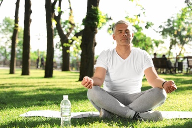 Photo of Handsome mature man practicing yoga in park, space for text. Healthy lifestyle
