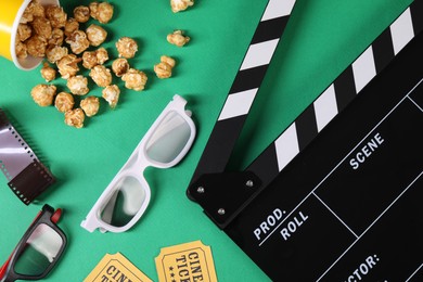 Flat lay composition with clapperboard, movie tickets and 3D glasses on green background