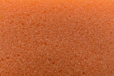 Photo of Orange cleaning sponge as background, top view