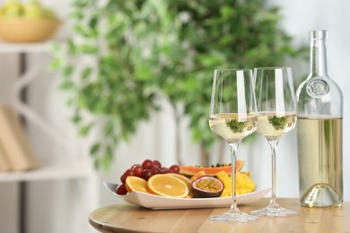 Photo of Delicious exotic fruits and wine on wooden table indoors, space for text