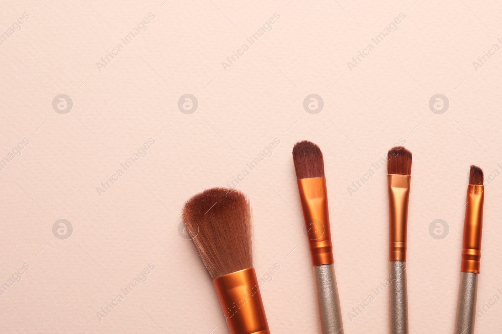 Photo of Set of makeup brushes on beige background, flat lay. Space for text