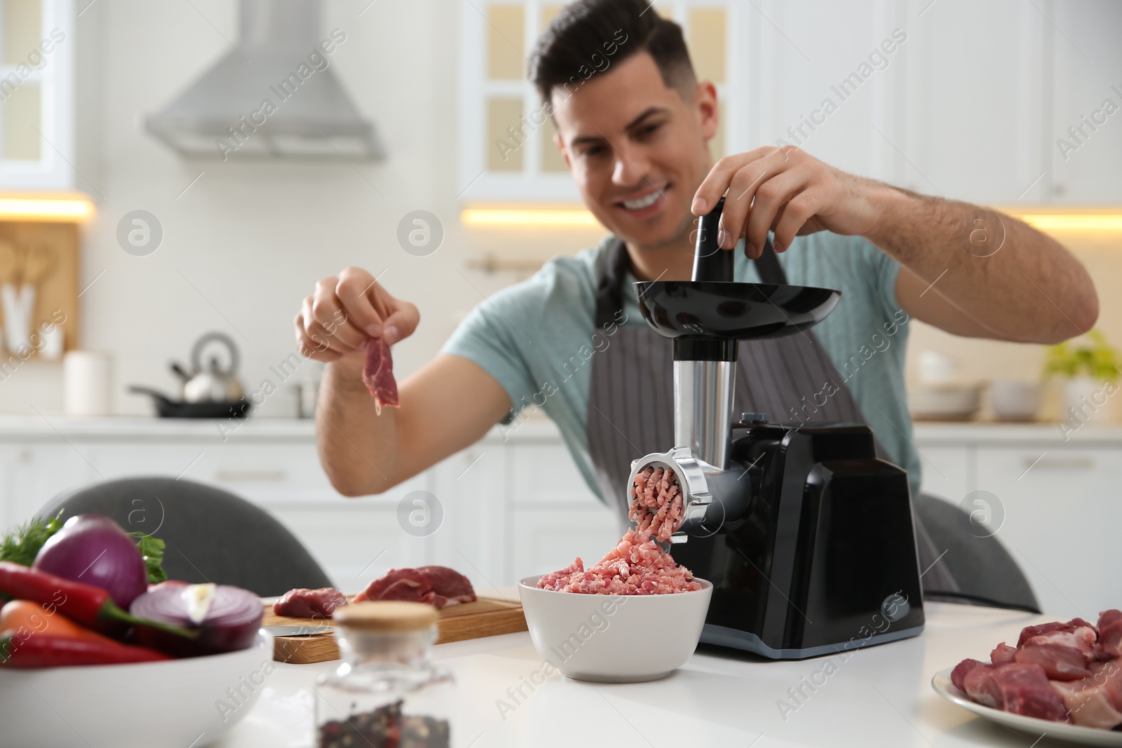 Photo of Man using modern meat grinder in kitchen