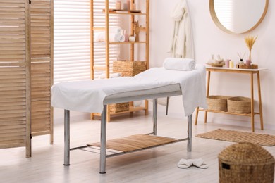 Photo of Comfortable massage table with clean towels in spa center