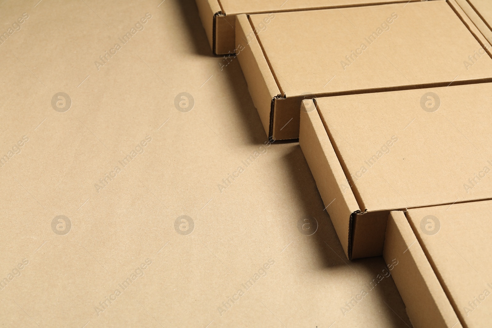 Photo of Many closed cardboard boxes on light brown background, closeup. Space for text