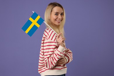 Image of Happy young woman with flag of Sweden on purple background