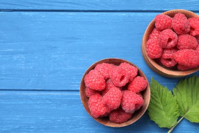 Photo of Delicious fresh ripe raspberries on blue wooden table, flat lay. Space for text