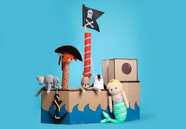 Photo of Pirate cardboard ship and toys on turquoise background