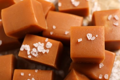 Photo of Tasty caramel candies and sea salt on table, closeup