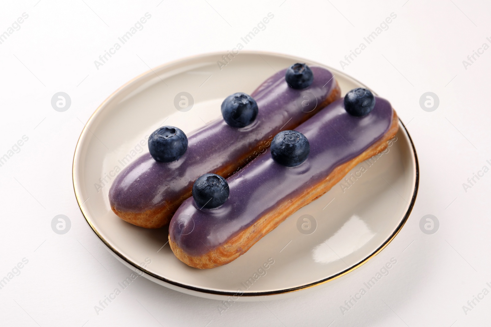 Photo of Delicious eclairs decorated with blueberries on white background