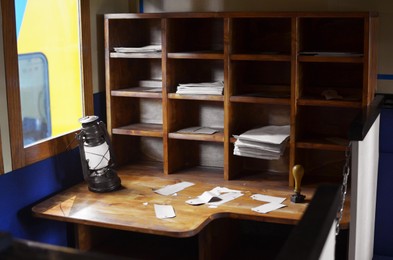 Photo of Wooden retro shelves and kerosene lamp on table indoors