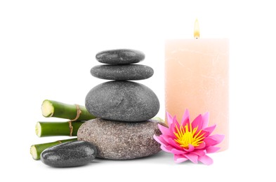 Photo of Stack of spa stones, bamboo stems, flower and candle isolated on white