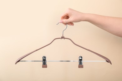 Woman holding hanger with clips on beige background, closeup