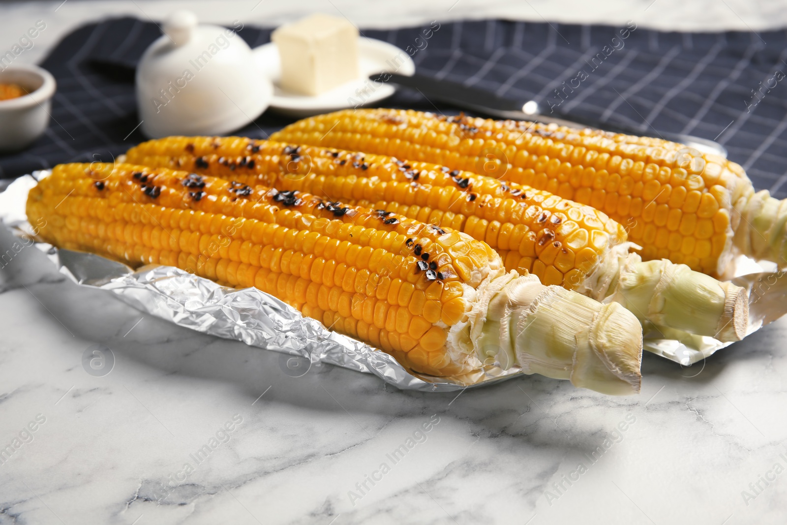 Photo of Fresh grilled tasty corn cobs served on marble table