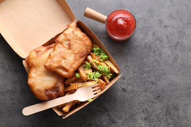 Photo of Tasty fish, chips, sauce and peas in paper box on grey table, top view. Space for text