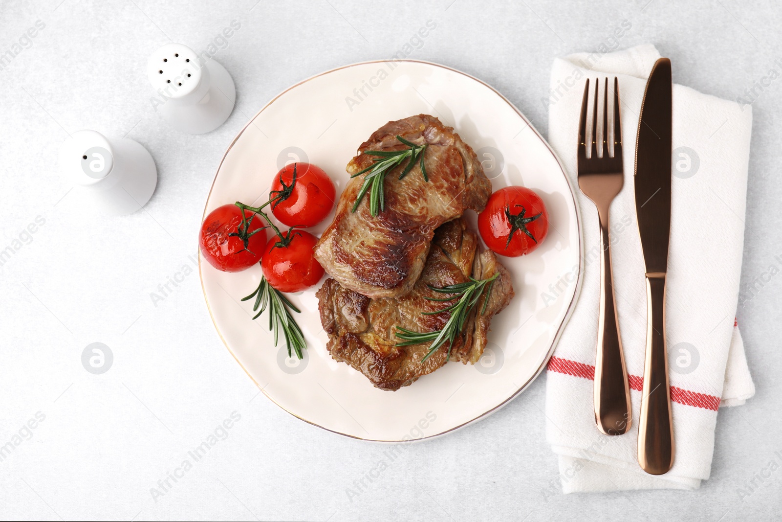 Photo of Delicious fried meat with rosemary and tomatoes served on light grey table, flat lay