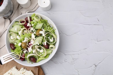 Bowl of tasty salad with leek, olives and cheese on white textured table, flat lay. Space for text