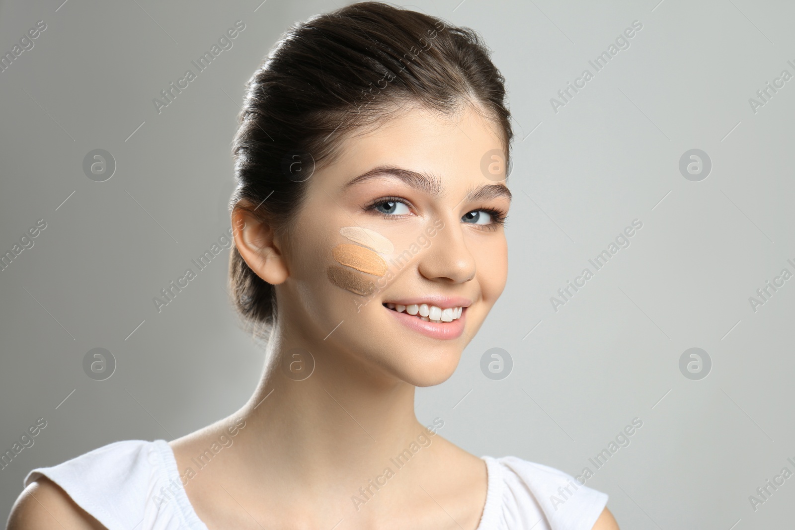 Photo of Beautiful girl on light grey background. Using concealer and foundation for face contouring