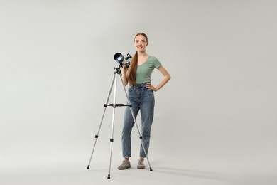 Photo of Happy young astronomer with telescope on grey background