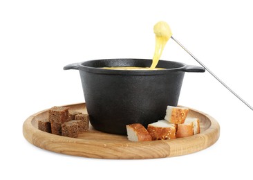 Dipping piece of bread into fondue pot with tasty melted cheese isolated on white