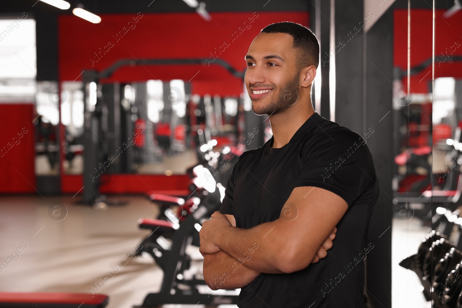 Photo of Happy trainer in modern gym, space for text