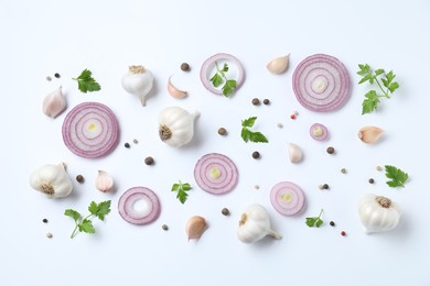 Fresh garlic, onion rings and spices on white table, flat lay