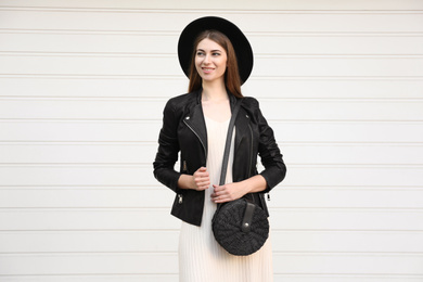 Photo of Beautiful young woman with stylish handbag near white wall
