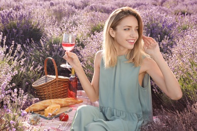 Photo of Young woman having picnic in lavender field