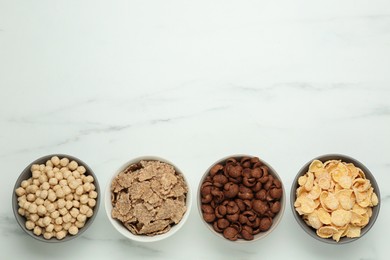 Different delicious breakfast cereals on white table, flat lay. Space for text