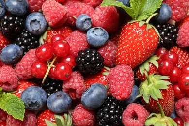 Mix of different fresh berries and mint as background, above view