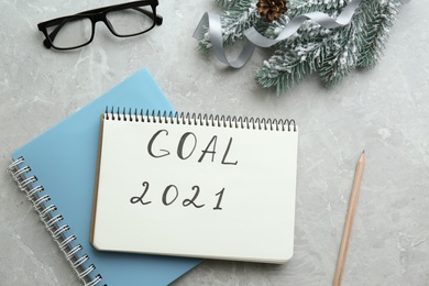 Photo of Notebook with text Goal 2021, new year targets. Flat lay composition on grey table