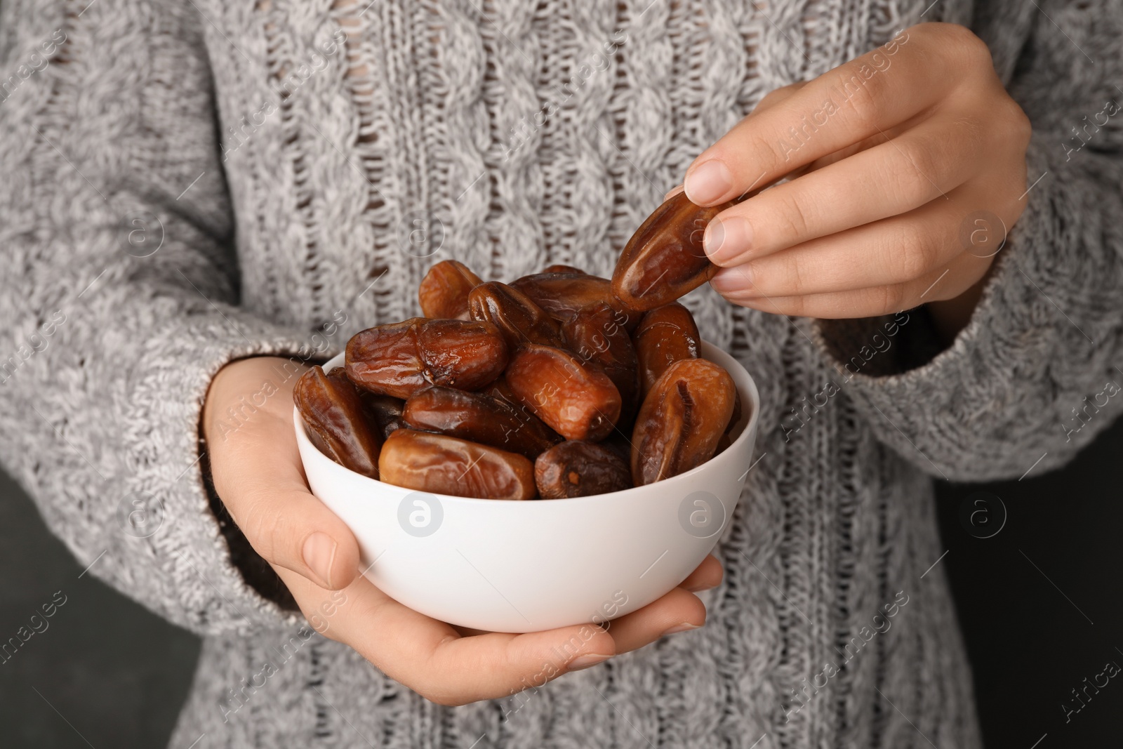 Photo of Woman holding bowl with tasty dried date fruits, closeup