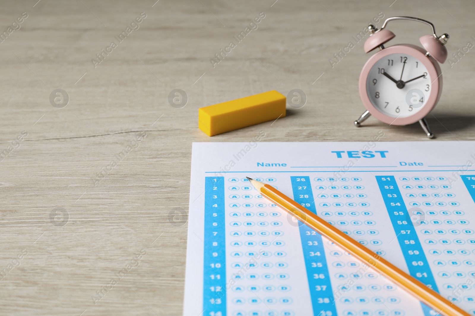 Photo of Answer sheet, pencil and alarm clock on wooden table, space for text. Student passing exam