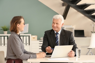 Photo of Mature man consulting with woman in office