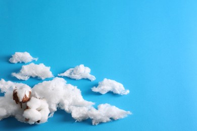 Photo of Clouds made of cotton and soft flowers on blue background. Space for text