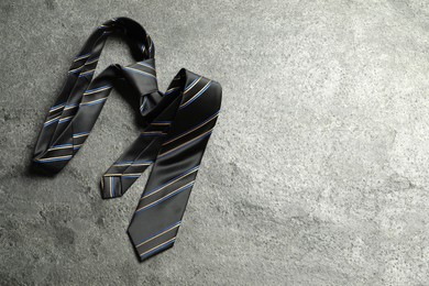 Photo of One striped necktie on grey textured background, top view. Space for text