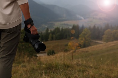 Photo of Professional photographer with modern camera in mountains, closeup. Space for text