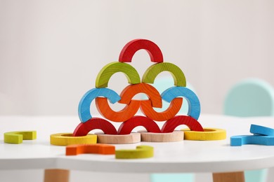 Colorful wooden pieces of playing set on white table indoors. Educational toy for motor skills development