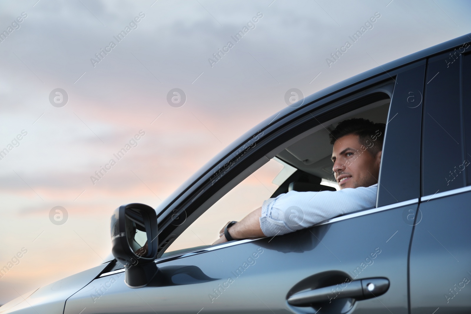 Photo of Handsome man driving his modern car, low angle view