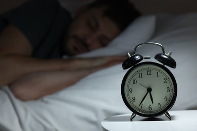 Photo of Man sleeping in bed, focus on alarm clock. Space for text