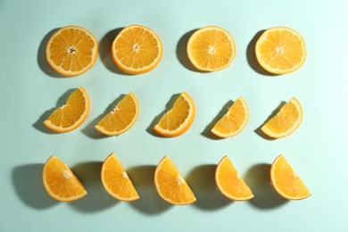 Cut fresh ripe oranges on light blue background, flat lay
