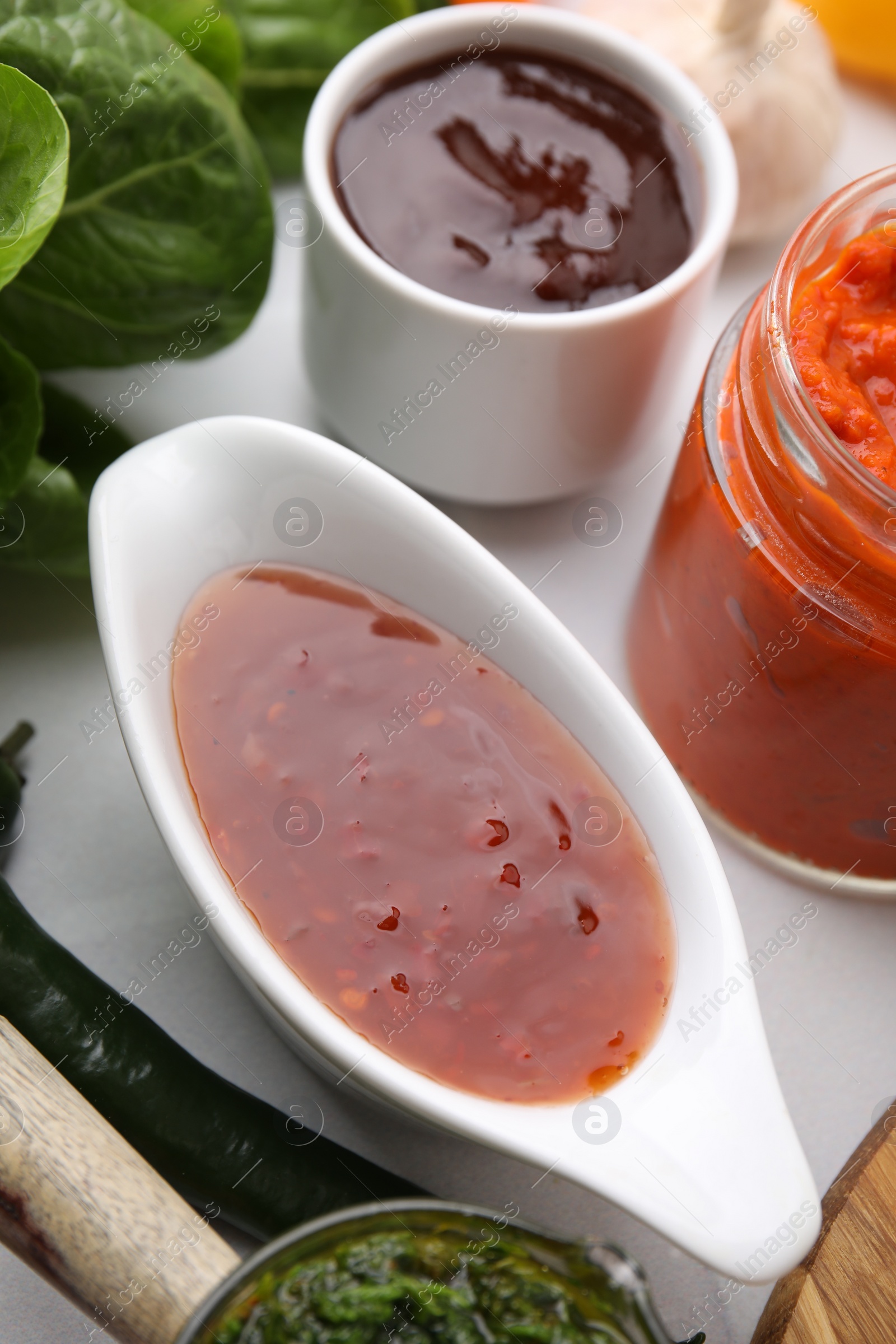 Photo of Different marinades in tableware on white table, closeup