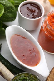 Photo of Different marinades in tableware on white table, closeup