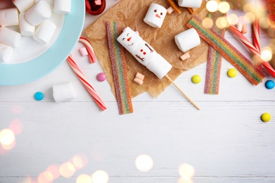 Image of Flat lay composition with funny snowman made of marshmallows on white wooden table, space for text. Bokeh effect 