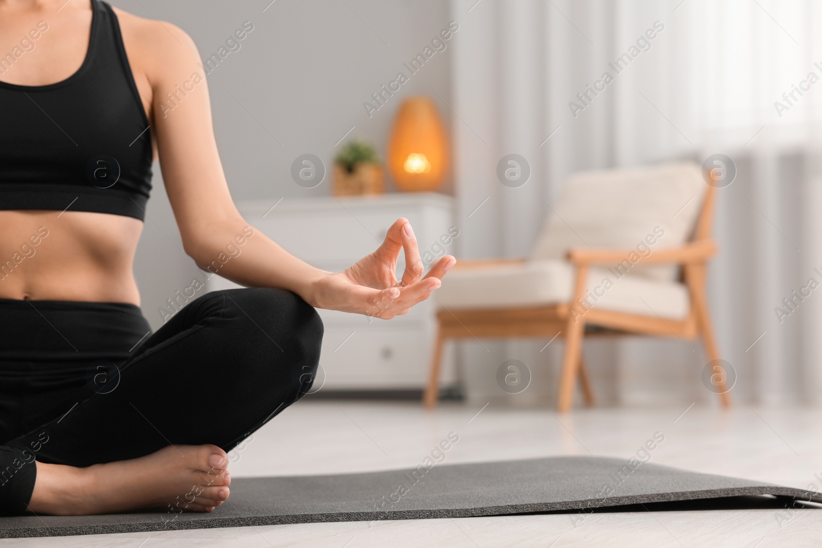 Photo of Woman practicing Padmasana on yoga mat at home, closeup and space for text. Lotus pose