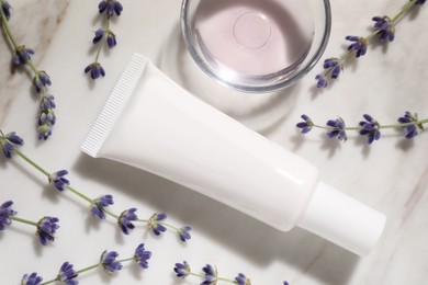 Photo of Tube of hand cream and lavender on marble table, flat lay