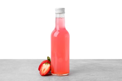 Delicious kombucha in glass bottle and strawberries on grey table against white background