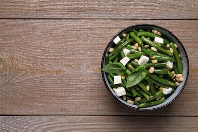 Photo of Delicious salad with green beans, pine nuts and cheese on wooden table, top view. Space for text