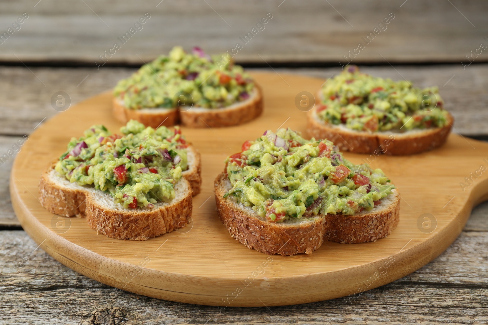 Photo of Slices of bread with tasty guacamole on wooden table, closeup