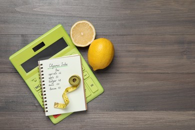 Photo of Notebook with products of low glycemic index, calculator, measuring tape and lemons on wooden table, flat lay. Space for text